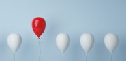 Ballon Konzept zu Führung und Freiheit mit einem roten Ballon in einer Gruppe weißer Ballons